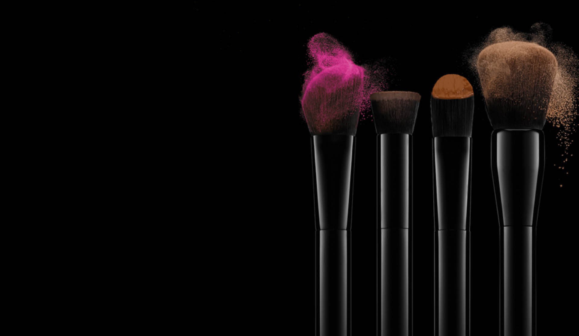 Brushes with coloured make-up on a dark background