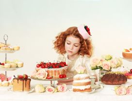 The girl looks long at cakes on the table