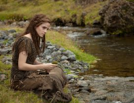 Emma Watson sitting on the grass on the river