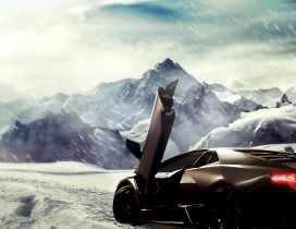 Brown Lamborghini in the snow between the mountains