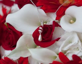 A necklace with a pearl on the white and red flowers