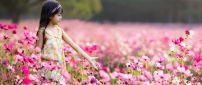 Little girl walking through a field full of pink flowers
