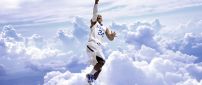 Basketball player with his ball in the air above the clouds