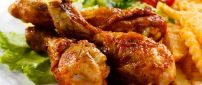 Chicken drumsticks and fries with salad and tomato