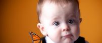 An orange butterfly on the shoulder of cute baby