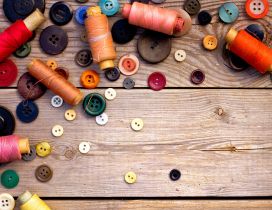 Threads and buttons in many colors on the wood