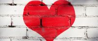 A big red heart painted on the wall made of brick