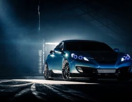 Blue Hyundai Genesis Coupe in a dark space