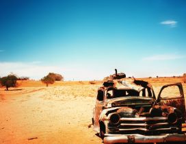 Old and very rusty classic car in the dessert