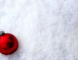 Shiny red Christmas ball in the white and cold snow