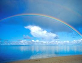 Beautiful rainbow over the blue ocean water - Sunny summer