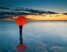 Abstract photo - Man with orange umbrella on a frozen water