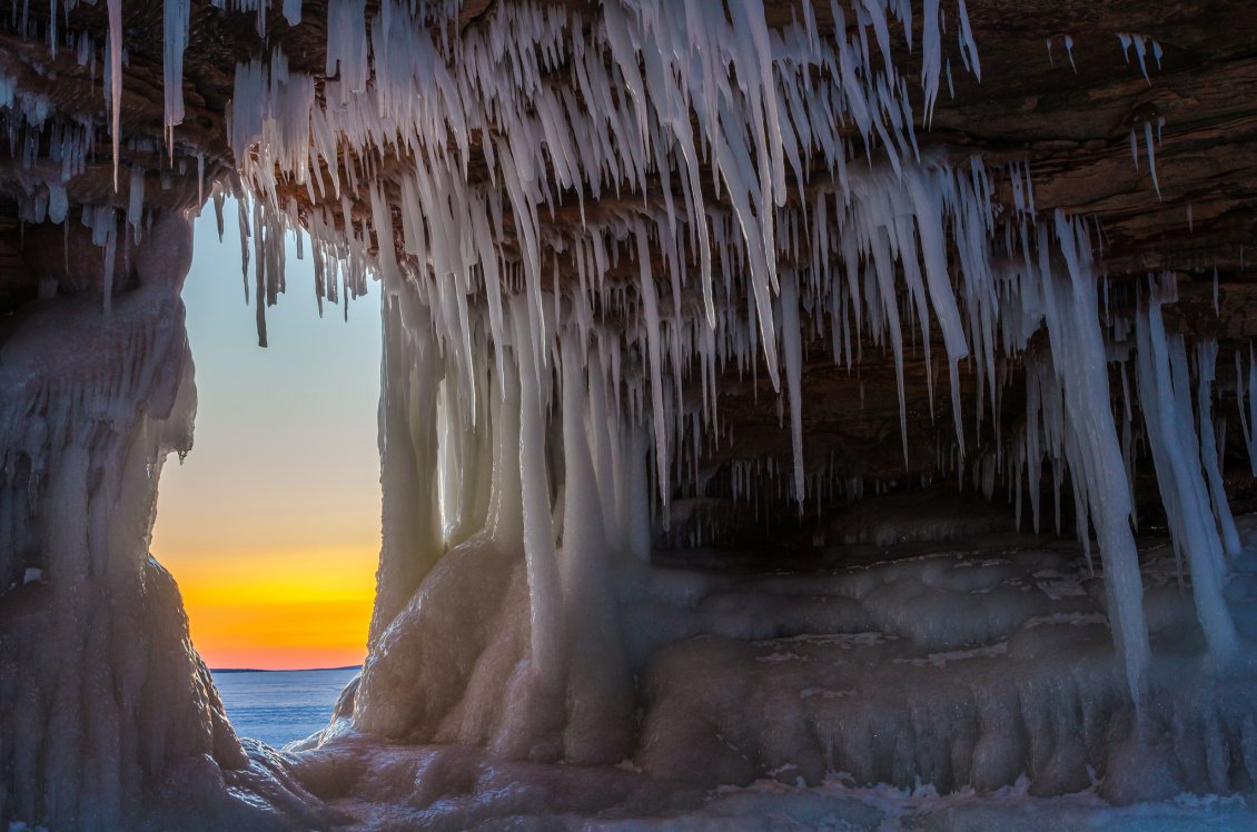 Download Wallpaper Sunset view from a cave full of icicle