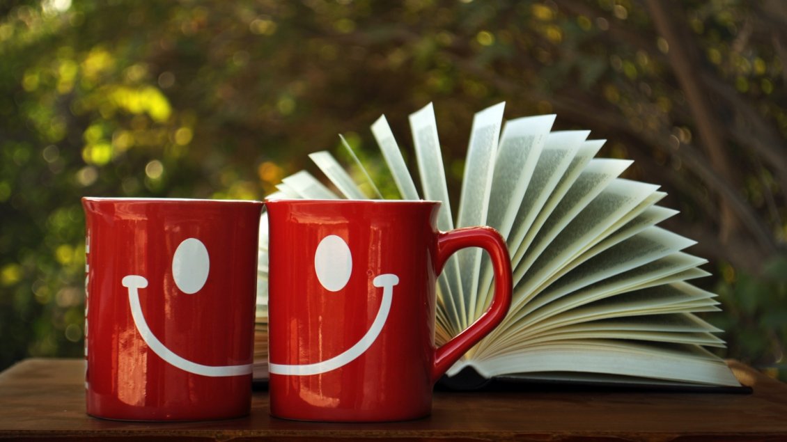 Download Wallpaper Two red cups with white smiles and a book