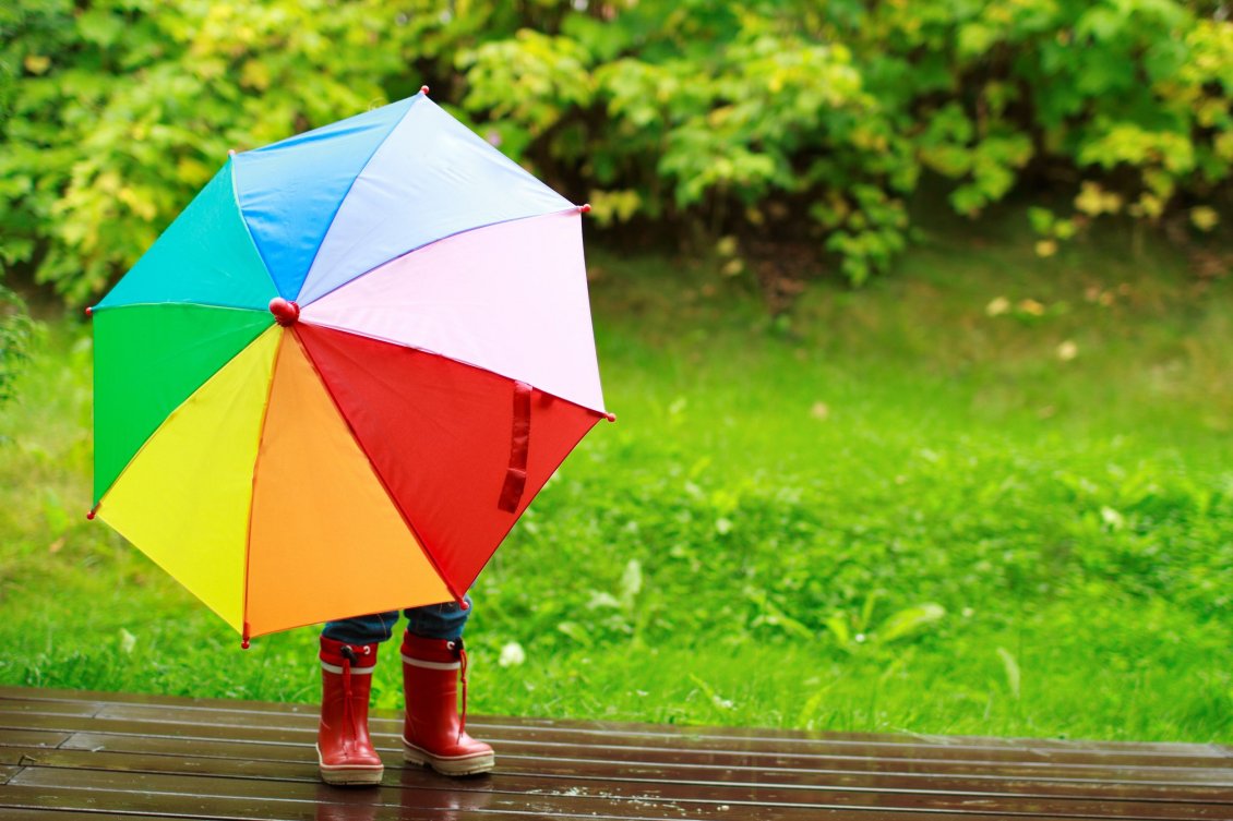 Download Wallpaper Little kid is playing in the rain with a colorful umbrella