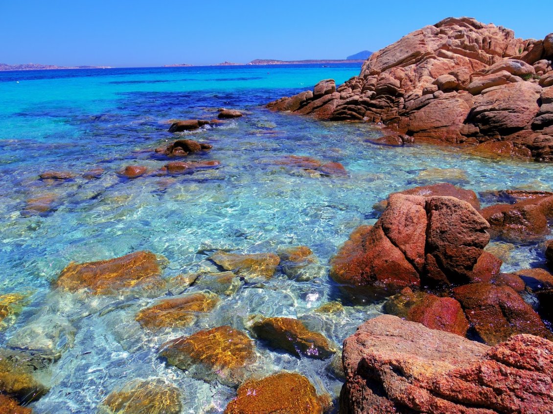 Download Wallpaper Rusty rocks in the blue ocean water - HD wallpaper