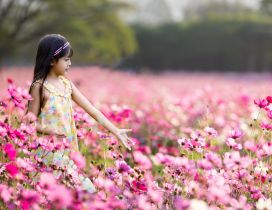 Little girl walking through a field full of pink flowers