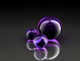 Three black and purple balloons of different sizes