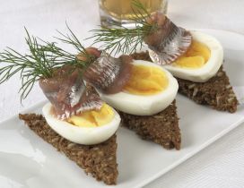 Three pieces of fish with boiled eggs on a plate