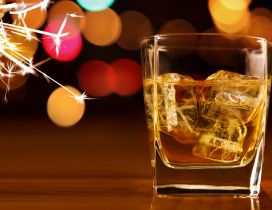 A glass of whisky with ice and fireworks in the night