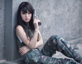 Hwang Mi Hee near the wall with a gun in hand