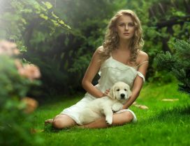 A girl with her white puppy on the grass in garden