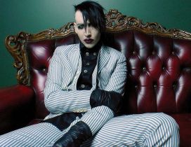 Marilyn Manson in a suit with stripes on the red sofa