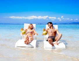 A couple relaxes on the sunbed in water