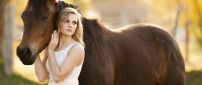 Pretty blonde girl and a brown horse