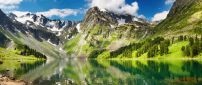 Green and white mountains reflected in the lake water