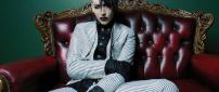 Marilyn Manson in a suit with stripes on the red sofa