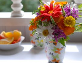 Many different colored flowers in a cup on the table