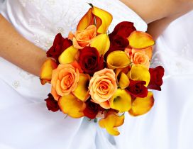 A bridal bouquet made of yellow callas and red roses