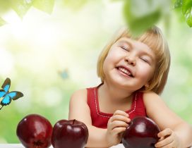 A sweet girl with a smile on face and with three red apples