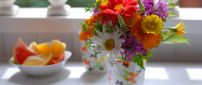 Many different colored flowers in a cup on the table