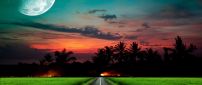 Straight road in the green field at sunset