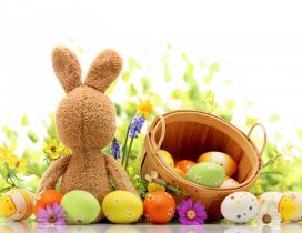 Funny rabbit and a basket with coloured Easter eggs