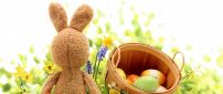 Funny rabbit and a basket with coloured Easter eggs